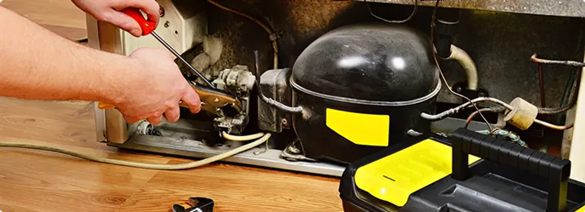 Refrigerator repair technician fixing the compressor and wiring in Rensselaer, NY