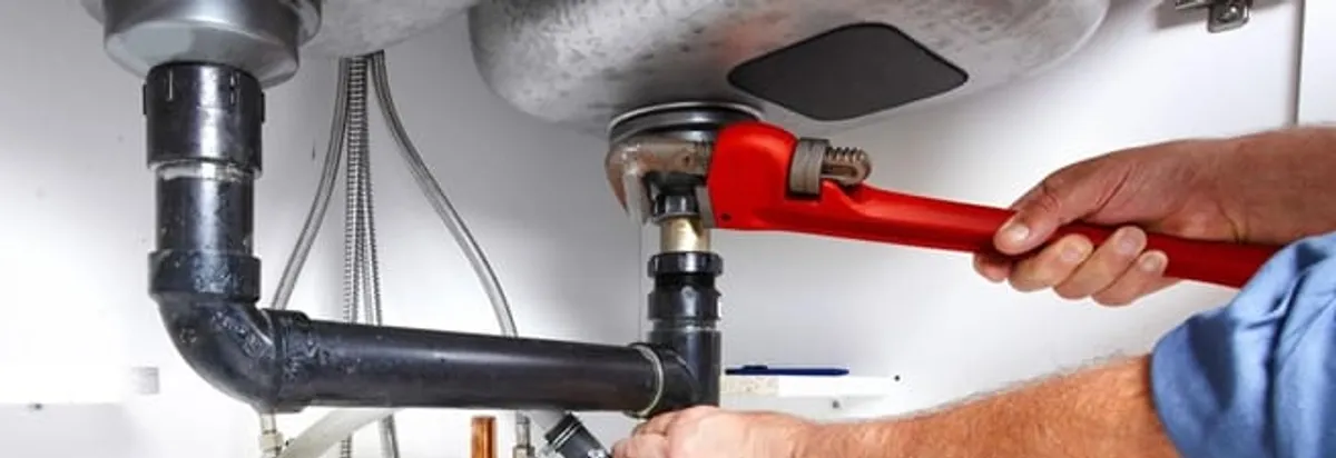 Garbage disposal repair technician tightening the sink drain and disposal connection in Albany, NY