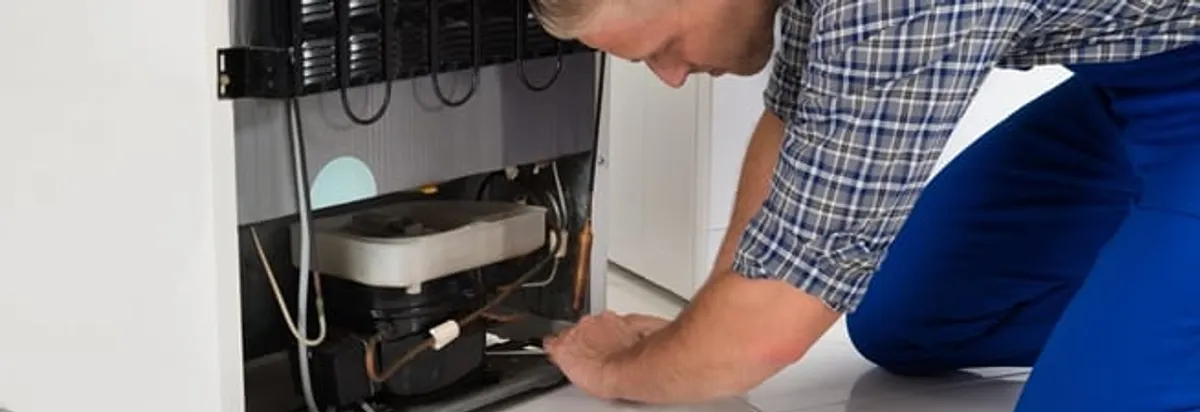 Refrigerator repair technician servicing the compressor and condenser area in Albany, NY